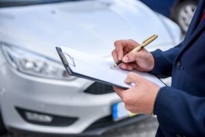 man with clipboard holding pen beside commercial vehicle writing