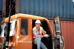 Commercial vehicle with door open and worker in hardhat smiling giving thumbs up.